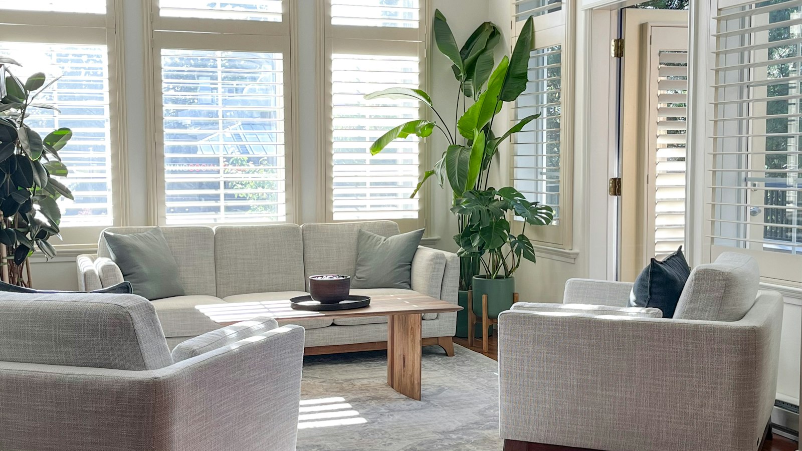 Bright living room with faux wood blinds on large windows, illustrating climate-appropriate window treatments
