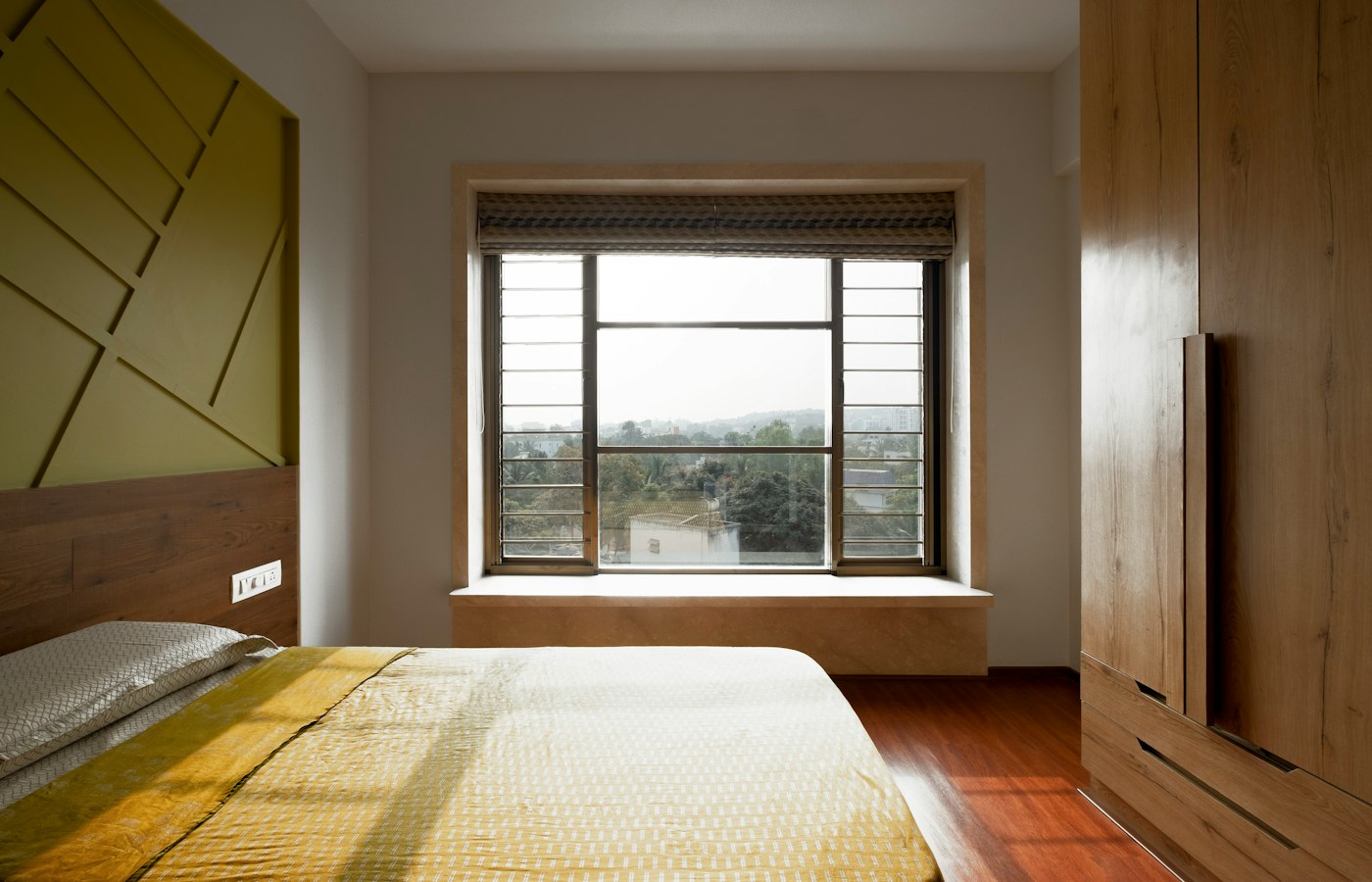 Honeycomb cellular shade raised at the top of a bright bedroom window