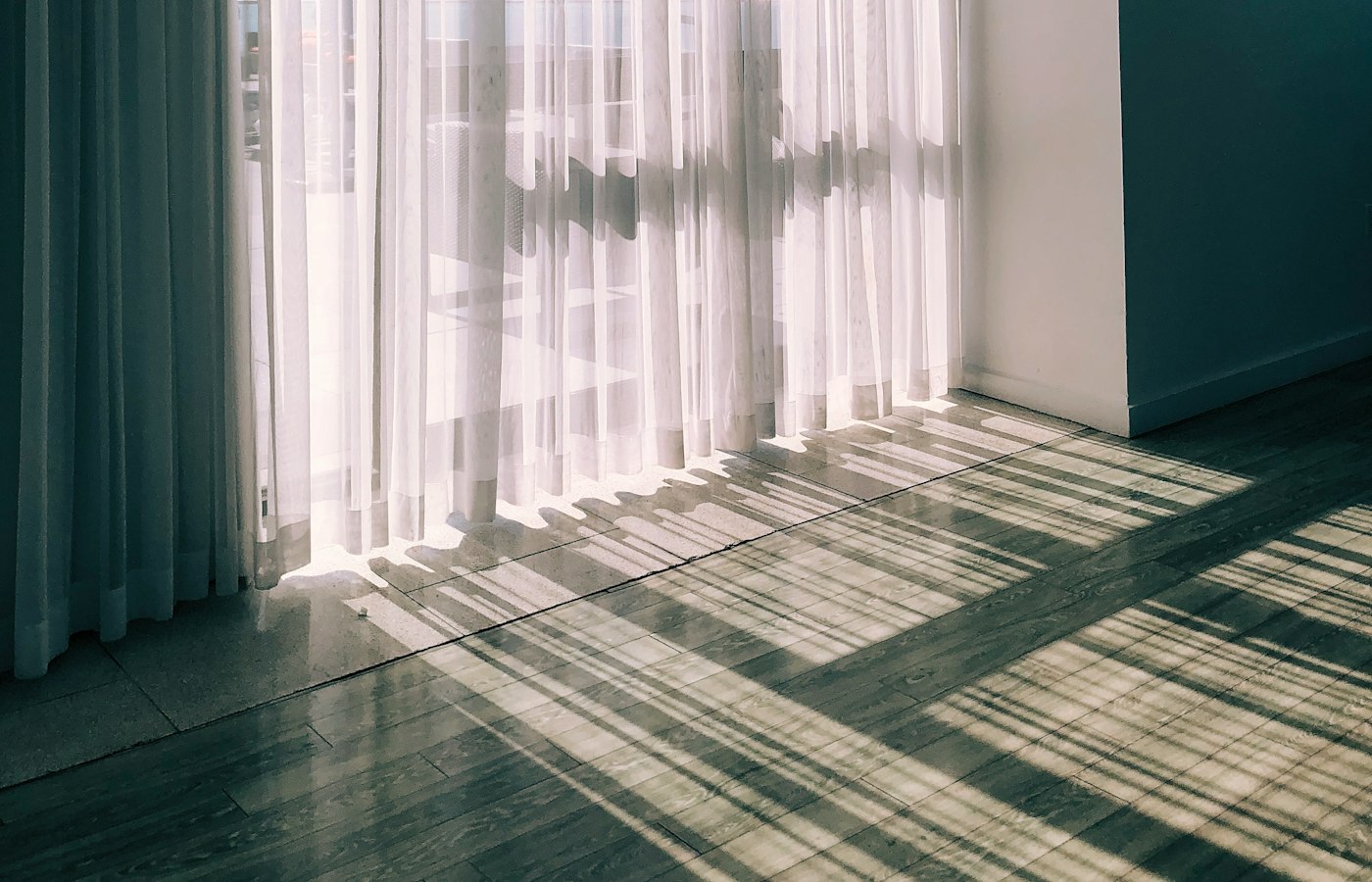 Sheer drapery panels layered over a window, filtering soft afternoon light